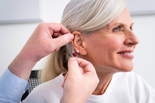 Ältere Frau erhält von Hörakustiker ein modernes Hörgerät zur Verbesserung des Hörvermögens.